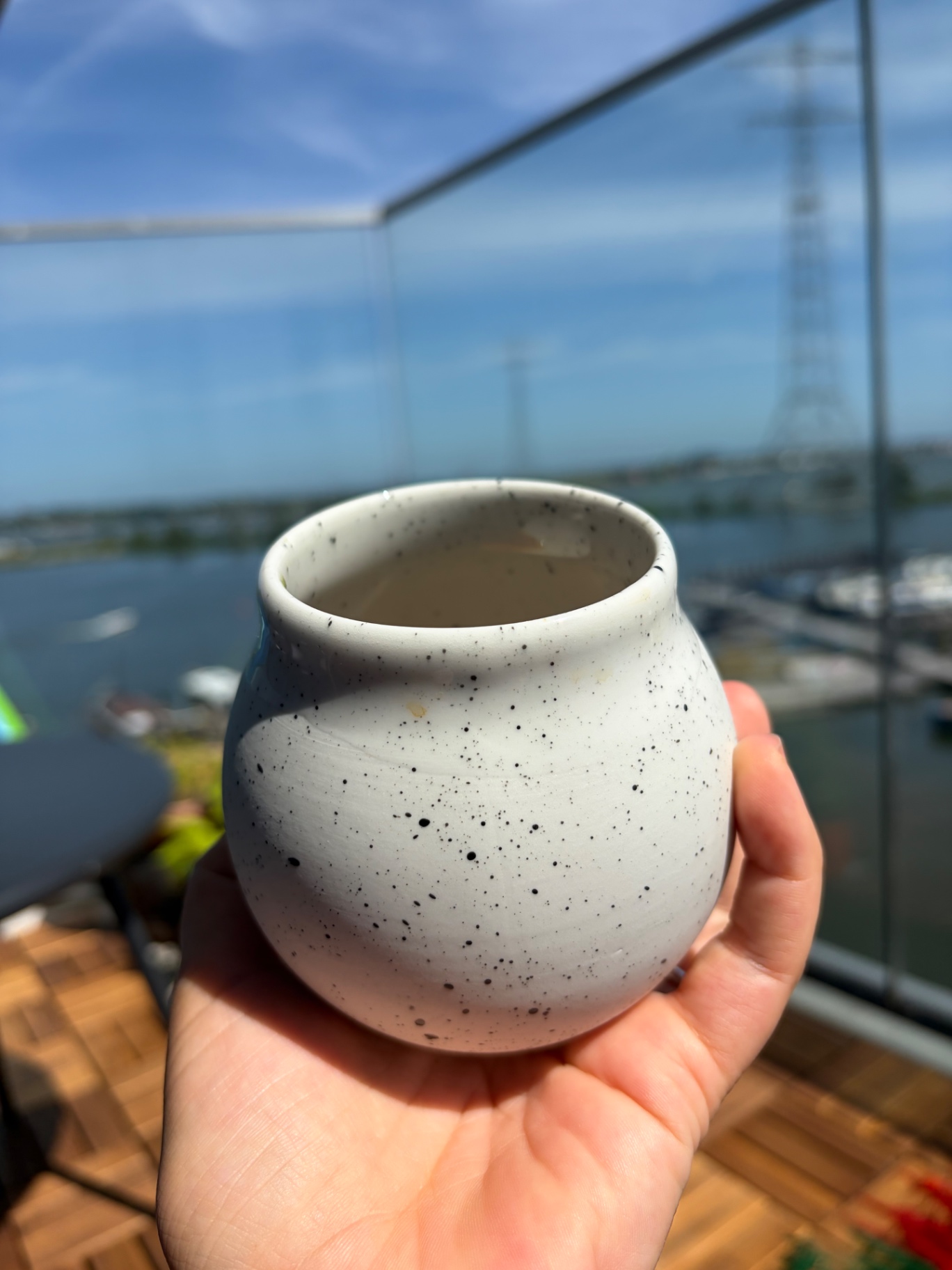 A specialty filter coffee cup by Studio Jie Chen, held against the light of the harbour